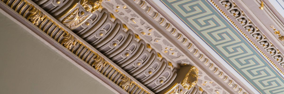 Stucco and luxurious decorative elements on ceiling. Luxury aesthetic in a home decor. Golden lion head pieces on a ceiling